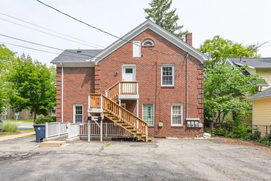 Brick house exterior with a staircase, windows and driveway